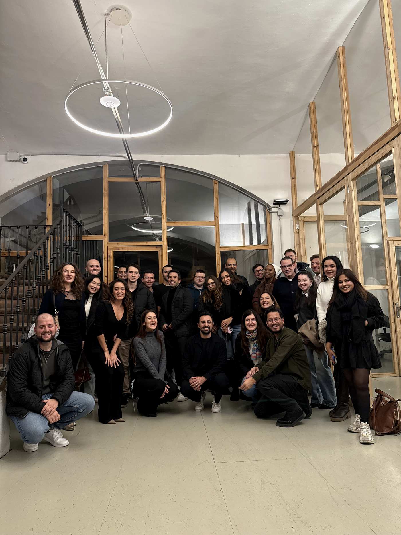Grupo posando bajo la estructura de arco y la carpintería de madera del espacio de Partners Academy en Barcelona